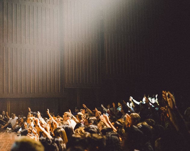 college students raise hands to answer a question in class