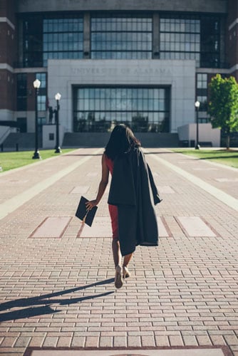 a college graduate walks across campus