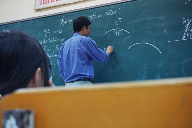 A teacher stands at a chalkboard writing