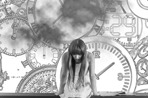 Woman waiting in front of wall filled with clocks