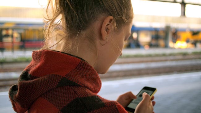 girl in plaid hoodie looking at her phone