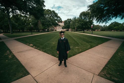 a graduate stands on campus