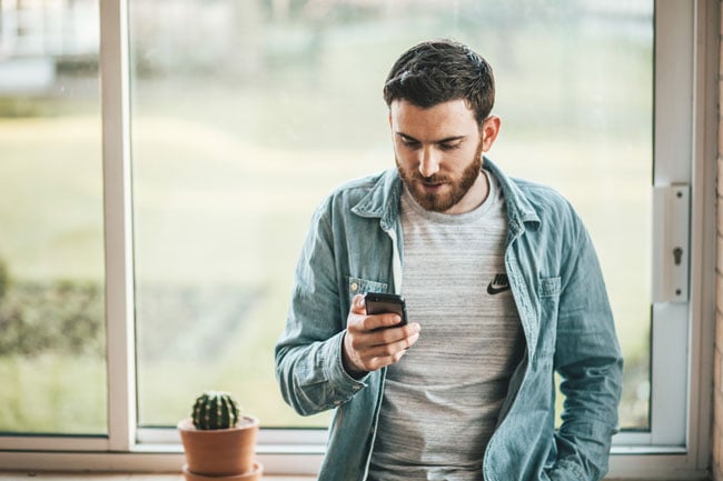 man holding a cell phone near a window