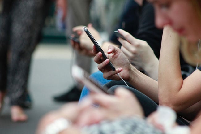 people sitting in a line looking at their phones