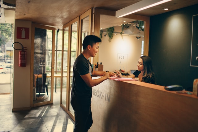 A man talks with a receptionist in an office setting.