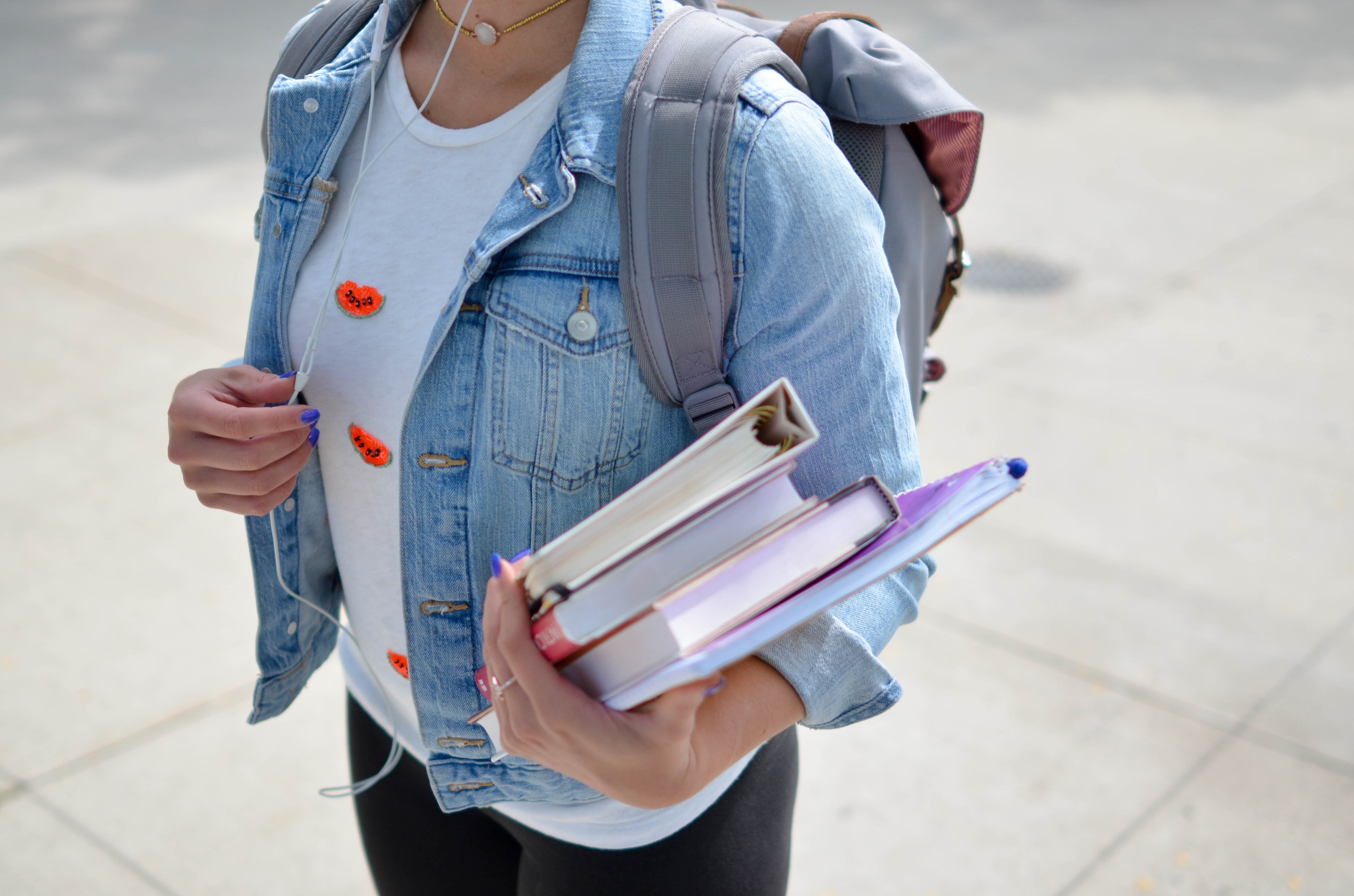 female student holding books wearing backpack