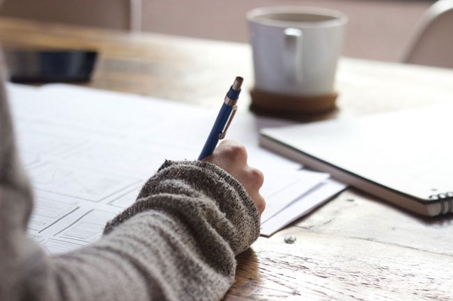 A person sits at a table taking notes on a large sheet of paper